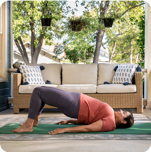 Women laying back, stretching her pelvis forward while feet is down on yoga mat.