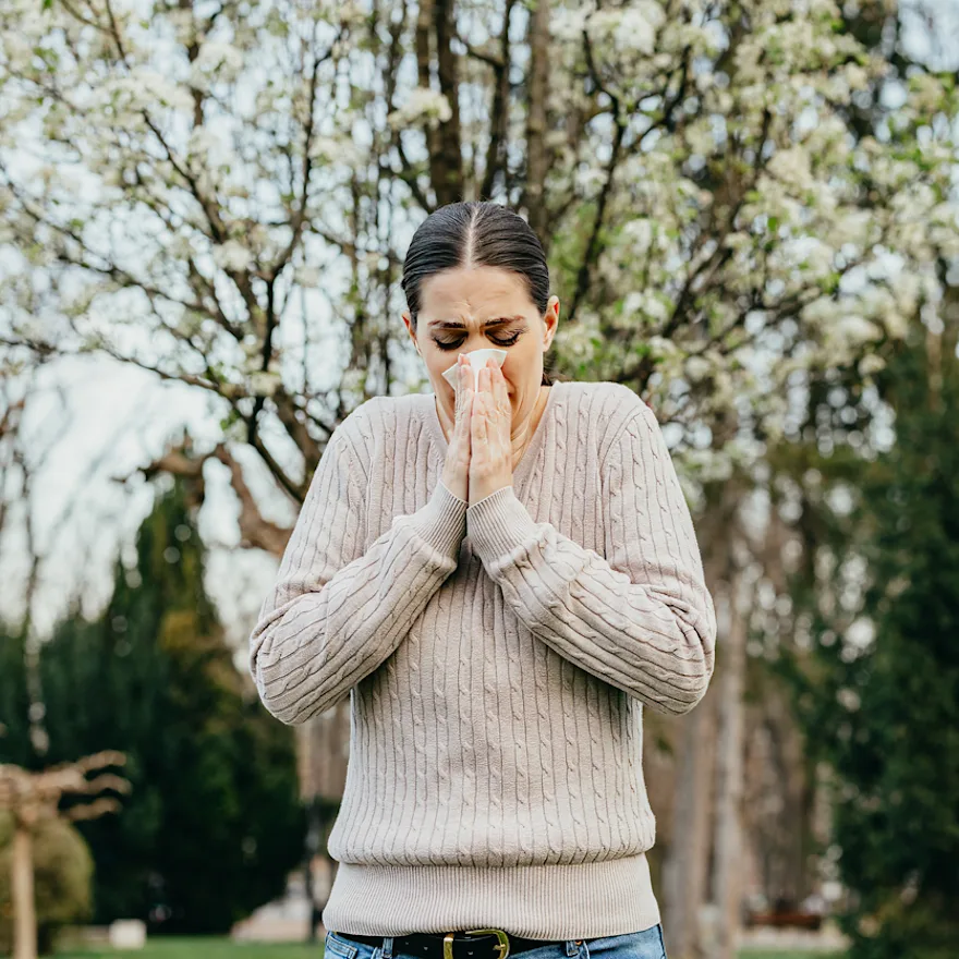 Woman in beige sweater experiencing stress incontinence.
