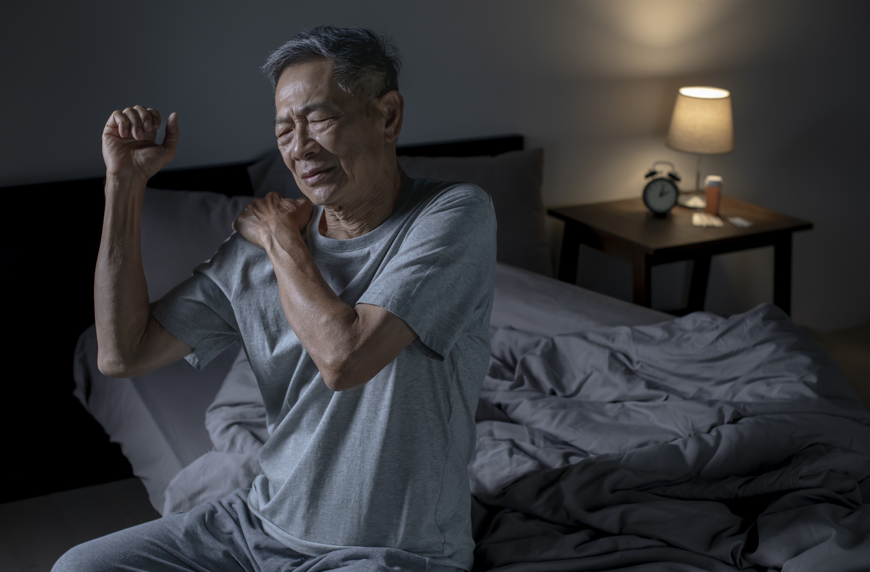 man feeling muscle spasm in shoulder