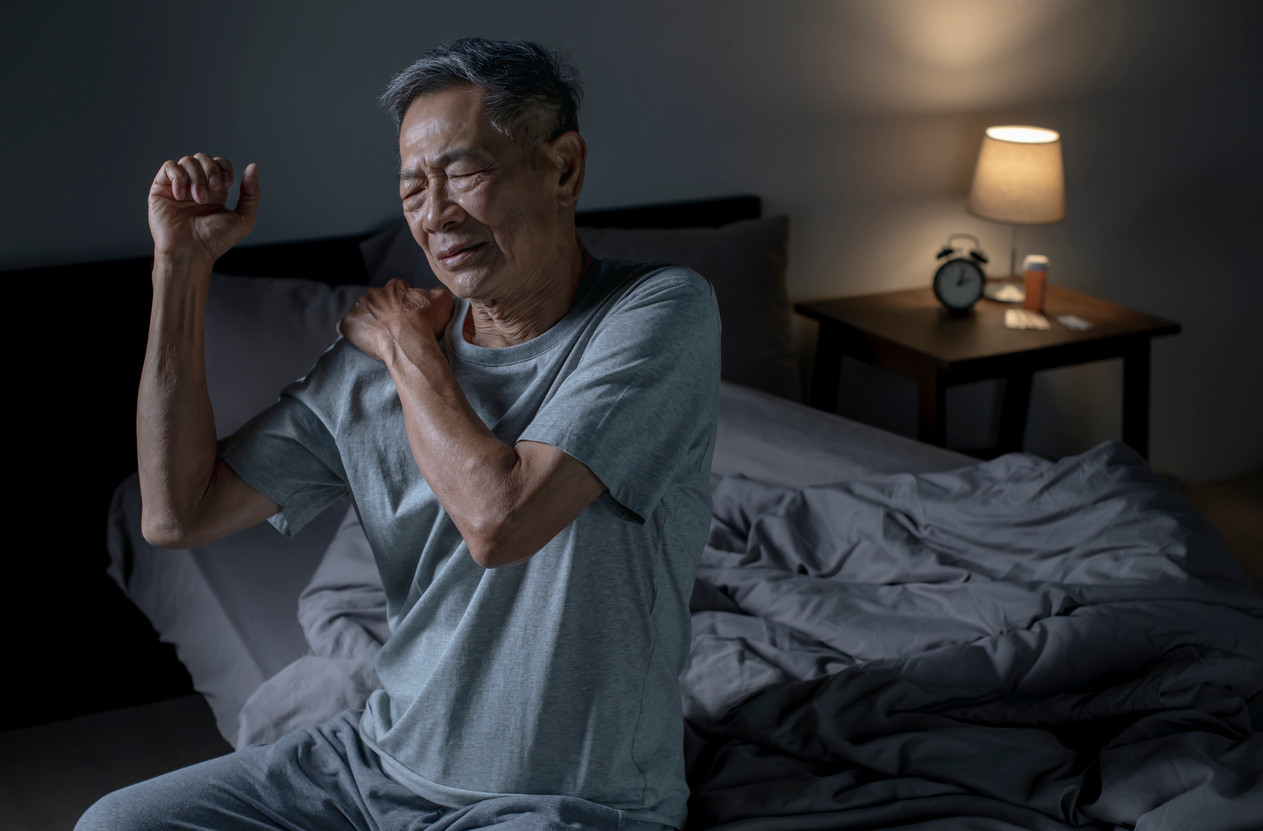man feeling muscle spasm in shoulder