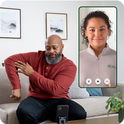Man holding elbow, speaking with a personal trainer through hinge health app