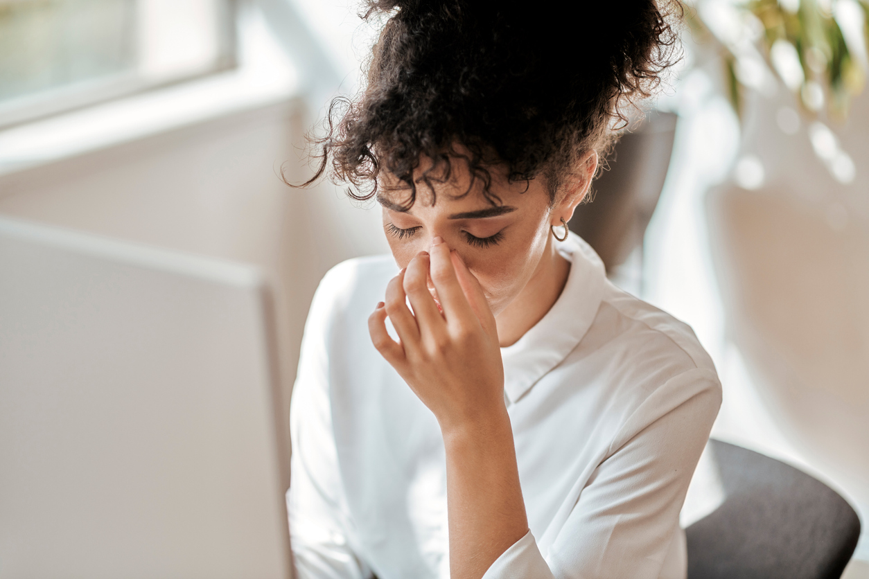 woman-at-her-workplace-closing-her-eyes-touching-forehead-with-stress