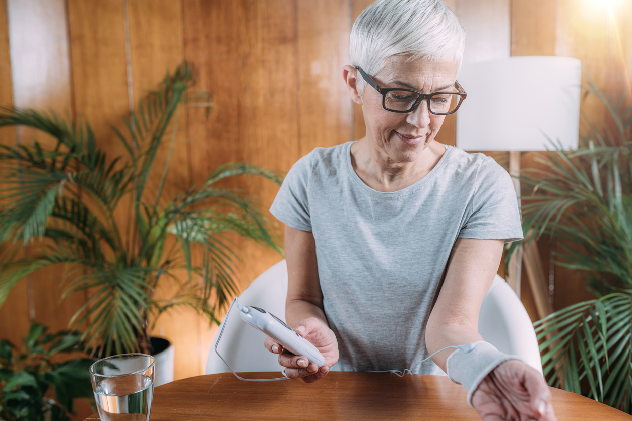 Senior Woman Doing Wrist Joint Physical Therapy with Conductive TENS Electrode Sock