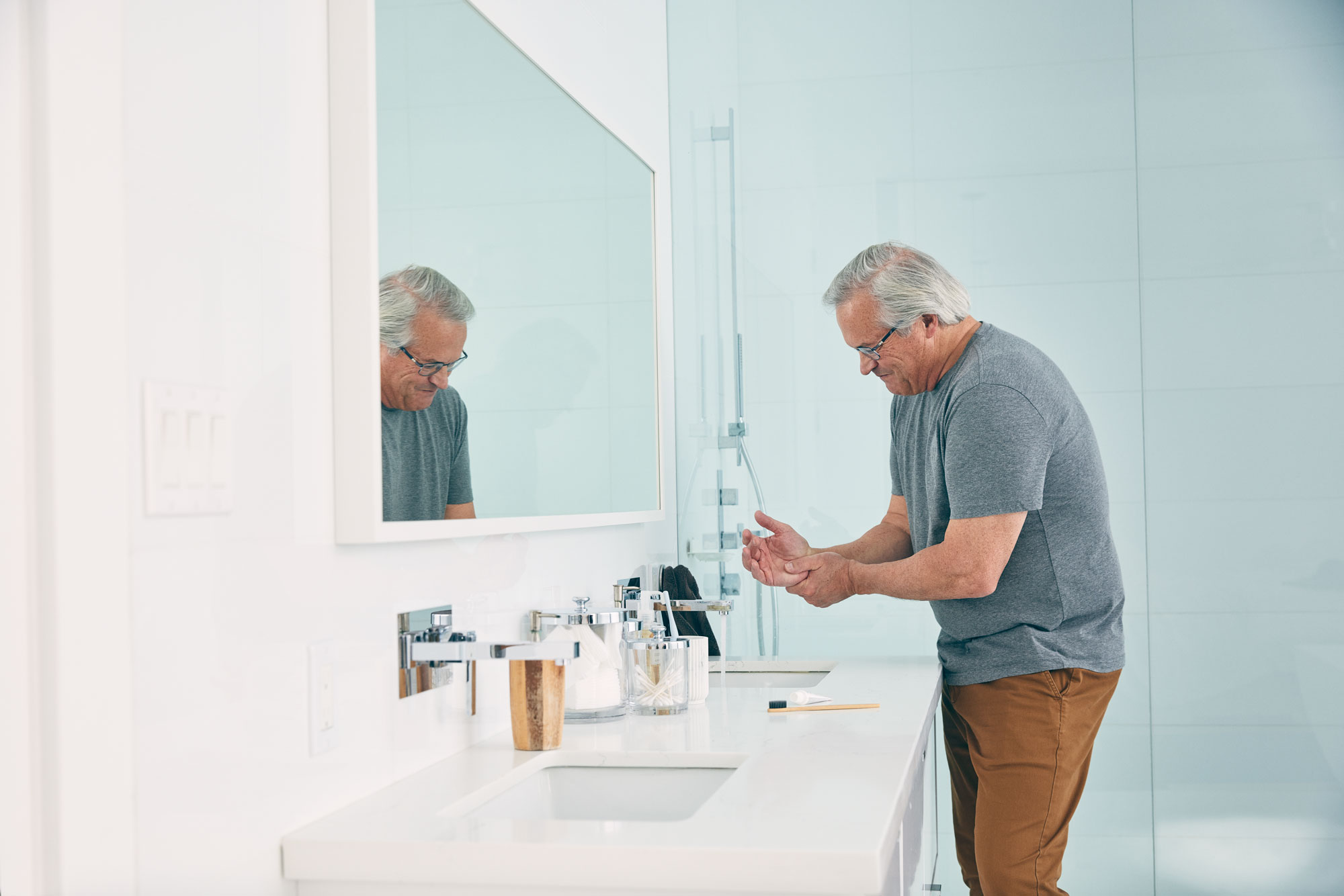 person in bathroom wincing at pain in hand