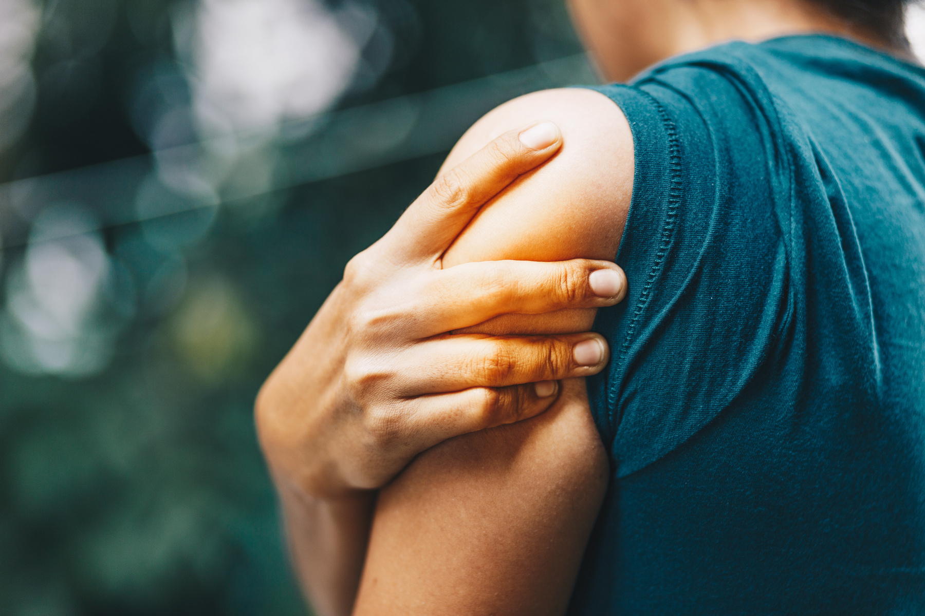 Person wearing green shirt massaging their arm