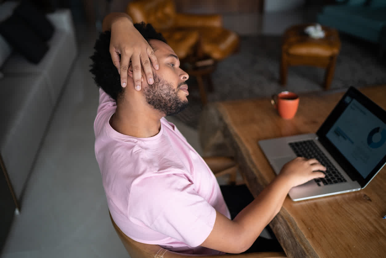 Man-stretching-his-neck-with-hand-while-working-from-home