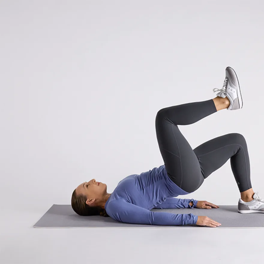 Person in blue long-sleeve top and black leggings performing a physical therapy exercises
