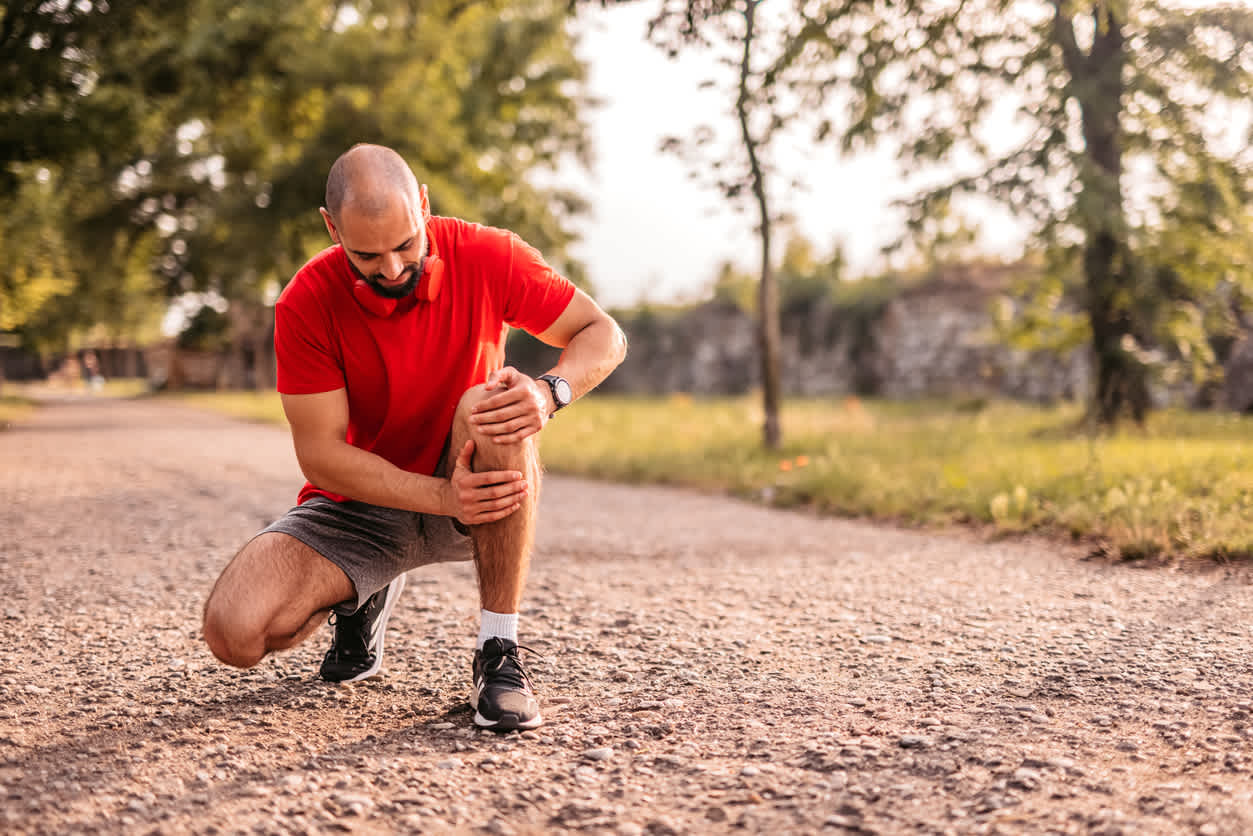Man-outdoors-holding-his-knee-in-pain-after-a-run