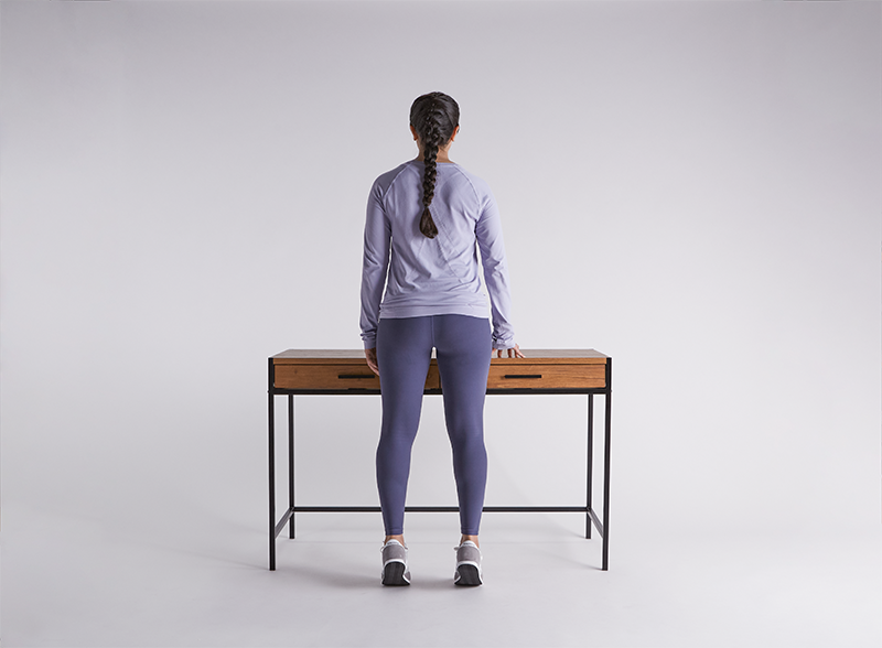 woman-doing-calf-raises-balancing-with-a-desk