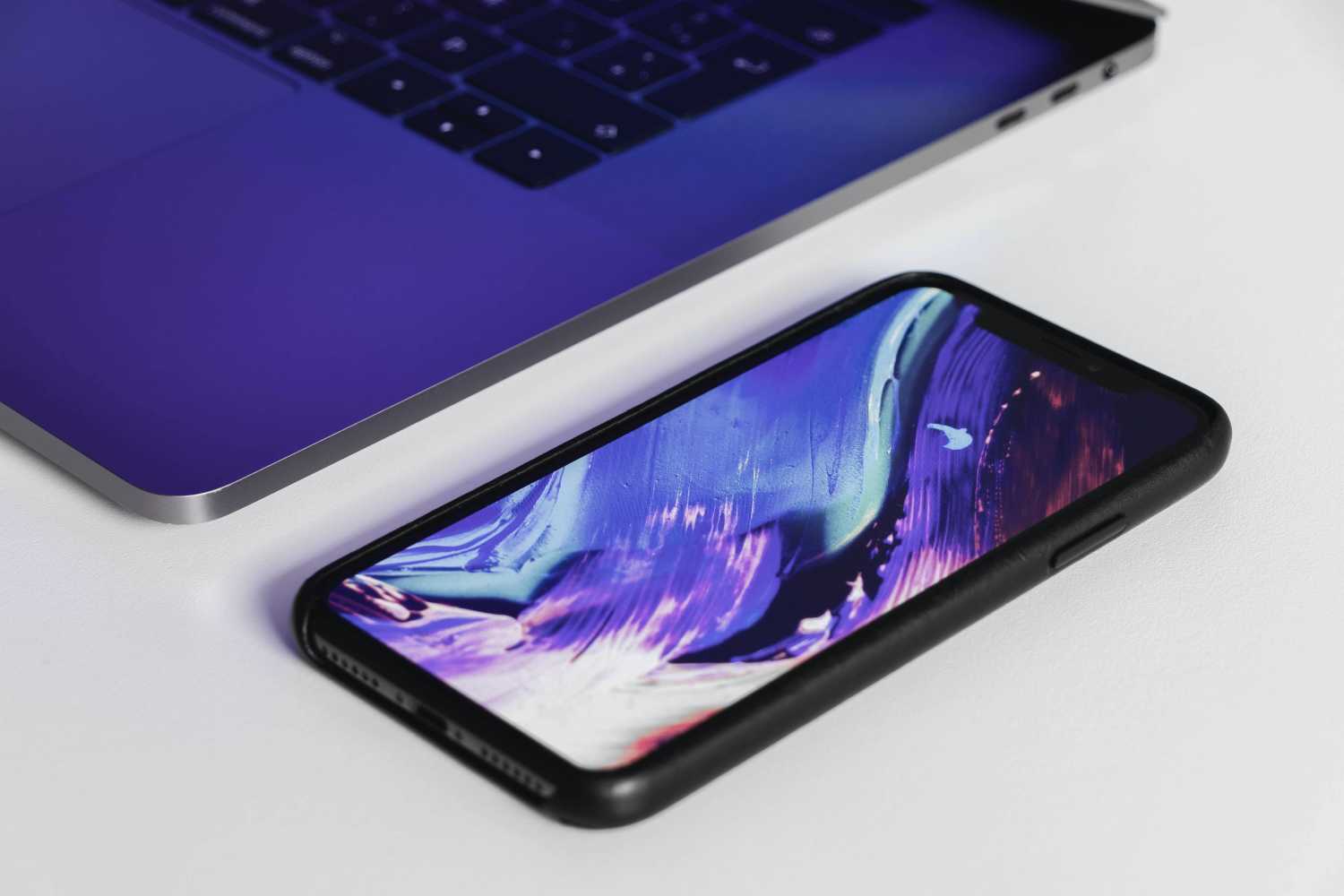 iPhone with colorful image next to MacBook