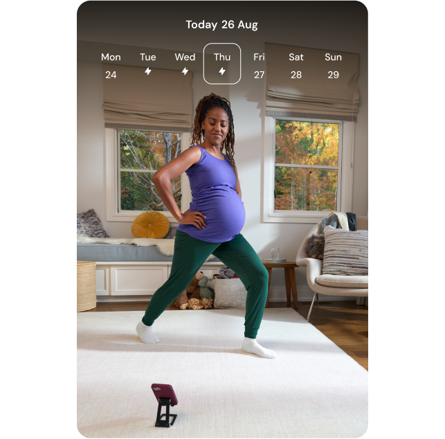 A pregnant woman is doing a hip flexor stretch in her living room as she follows along with the Hinge Health app, which is showing the same exercise with a "Start exercise" button.