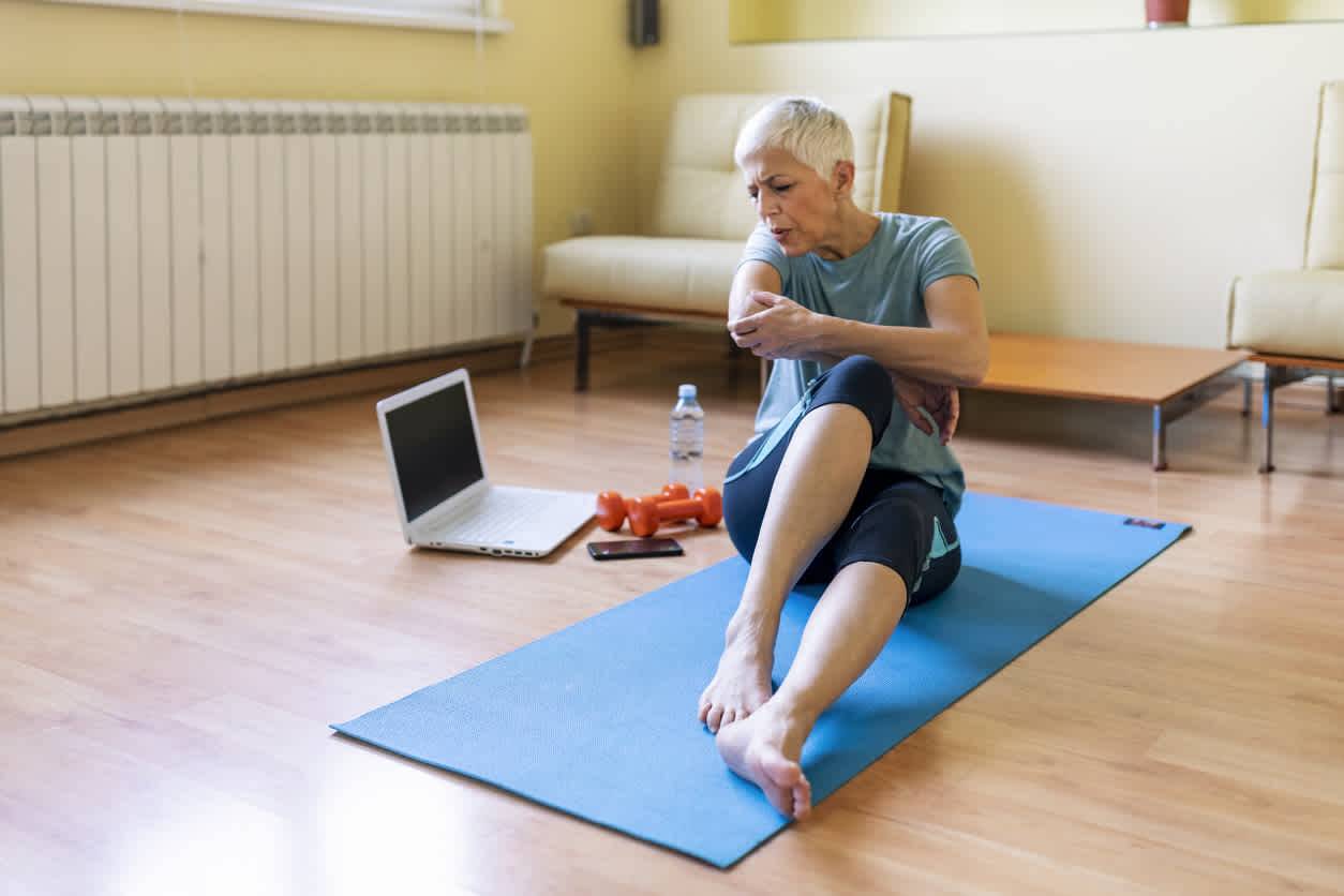 Elderly-woman-holding-her-elbow-in-pain-while-working-out-at-home