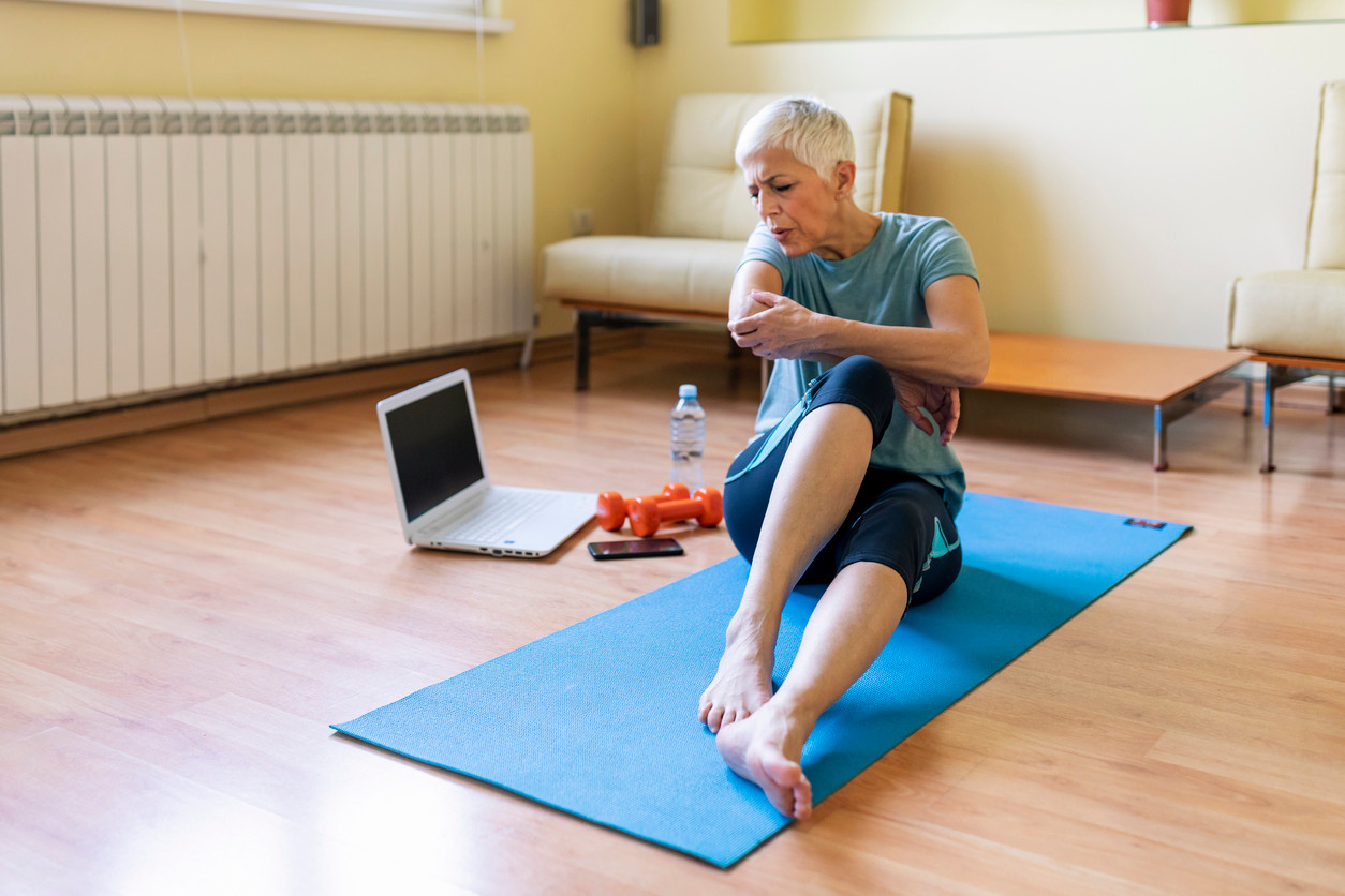 Elderly-woman-holding-her-elbow-in-pain-while-working-out-at-home
