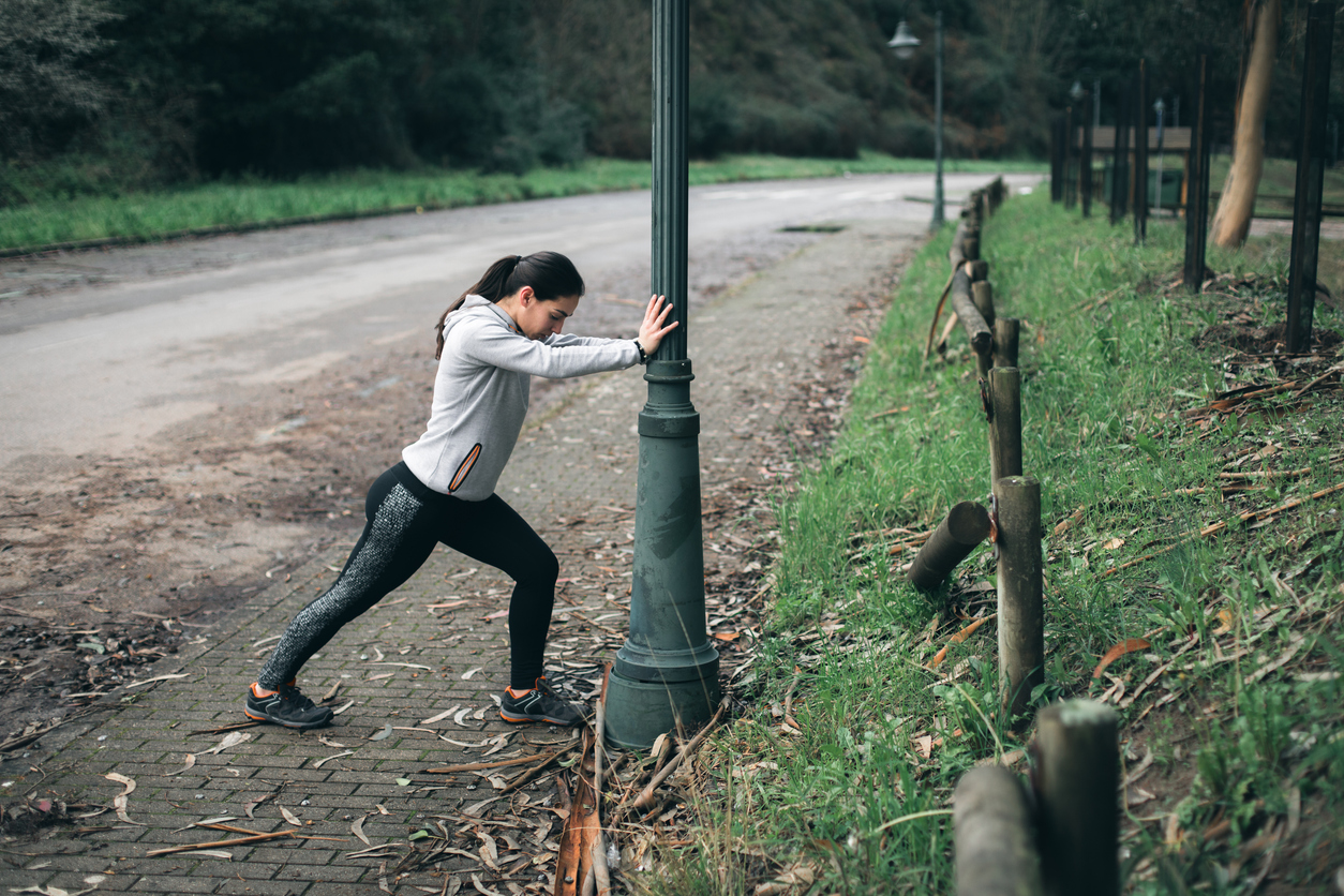 Person in training clothes stretching in the street.