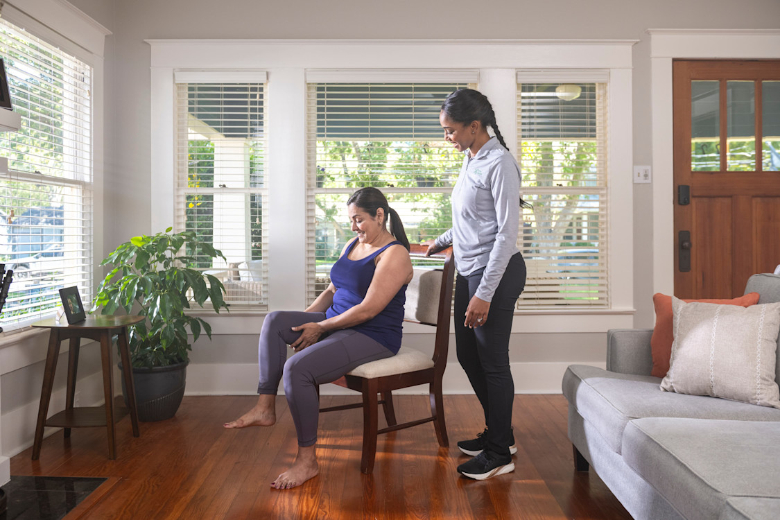 Woman stands over other woman while she stretches