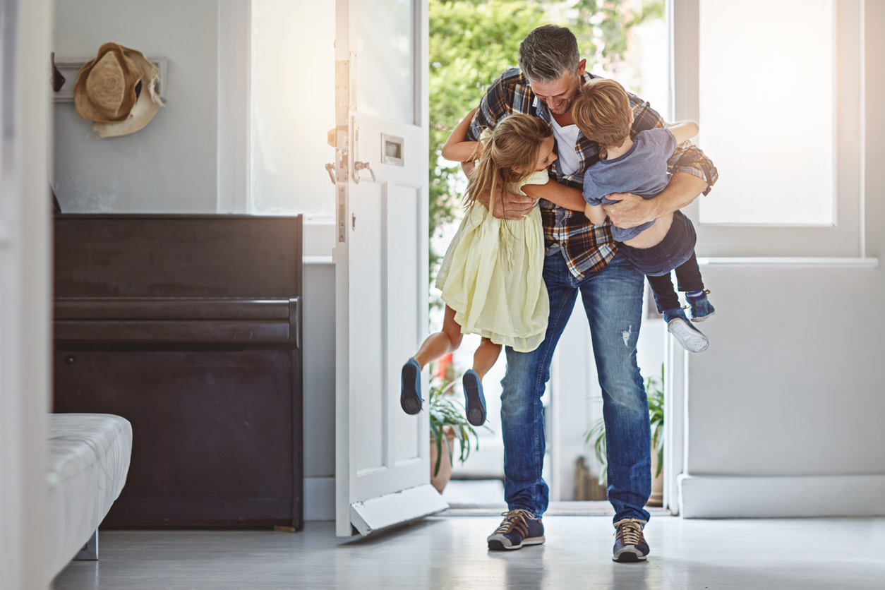Image of man bending over and picking up two kids.