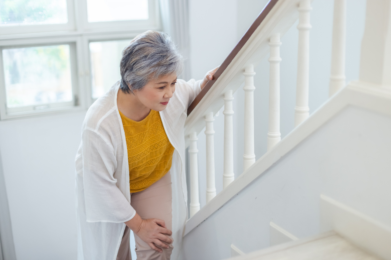 Woman-holding-her-knee-on-the-floor-at-stairs