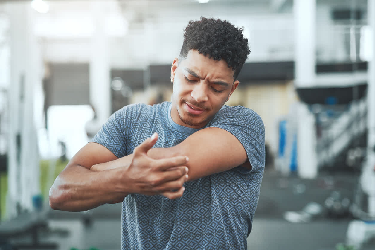 man-holding-his-elbow-in-pain-at-gym