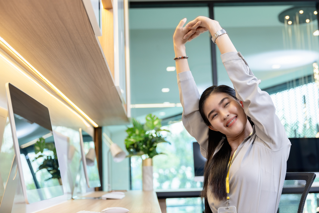 Professional performing exercises to improve posture at desk in modern office 