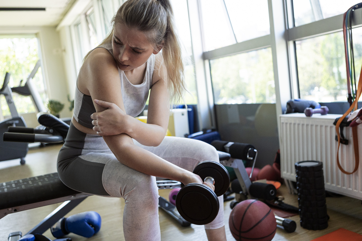 Woman sitting holding her arm due to latissimus dorsi pain