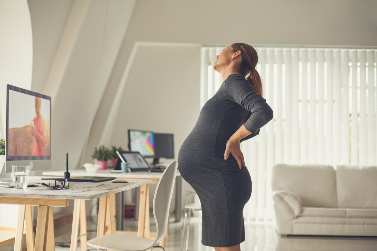 Pregnant woman experiencing SI joint pain in her office.