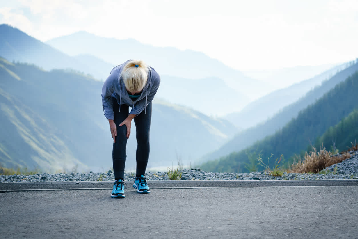 Older-woman-running-oudoors-touching-her-knee-in-pain