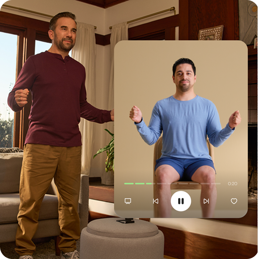 A man stands in his sunlit living room with arms raised. A closeup of the Hinge Health app shows the guided exercise session he’s following along.