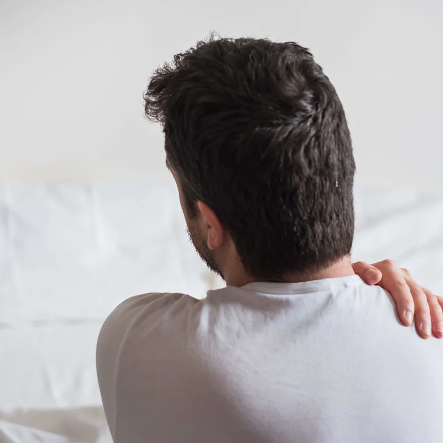Photo of a man robbing his shoulder with his left hand