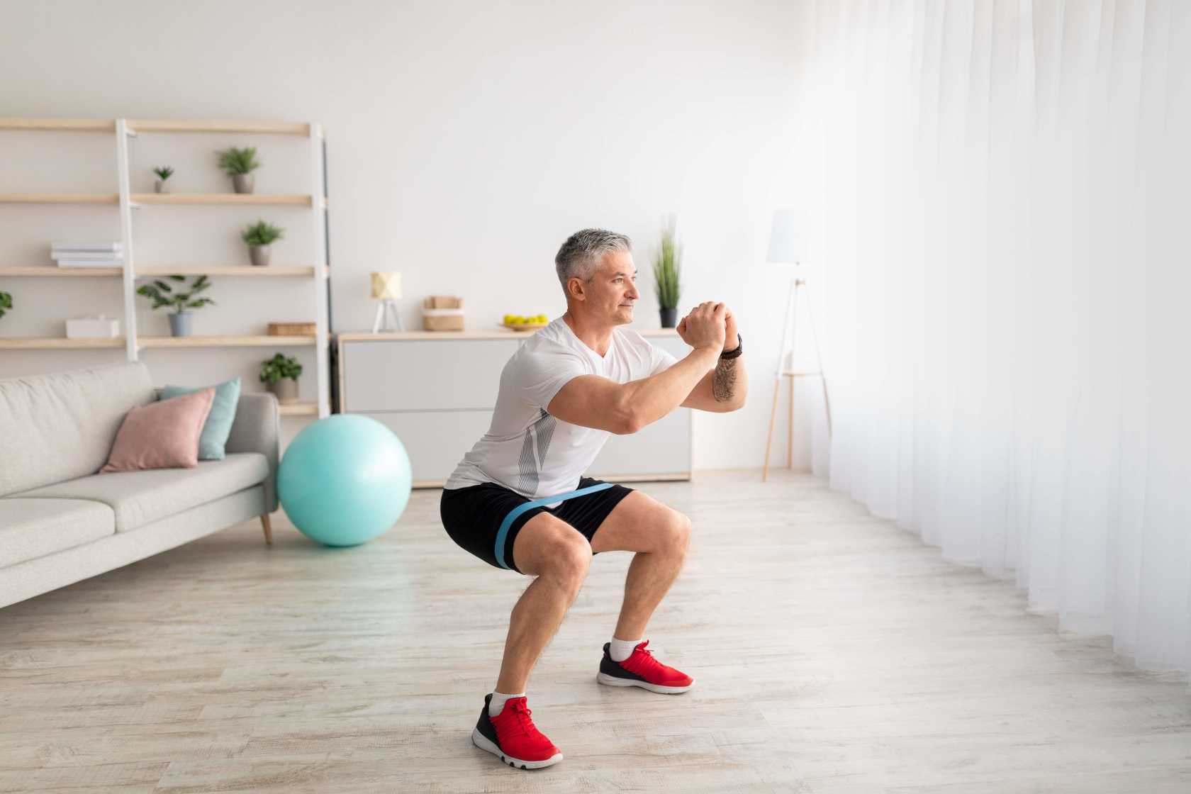 Man-doing-squats-with-resistant-band-at-home