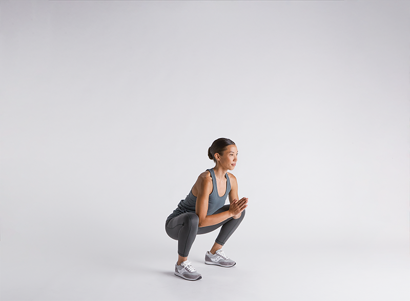 Woman-doing-deep-squat-on-grey-background-and-workout-clothes
