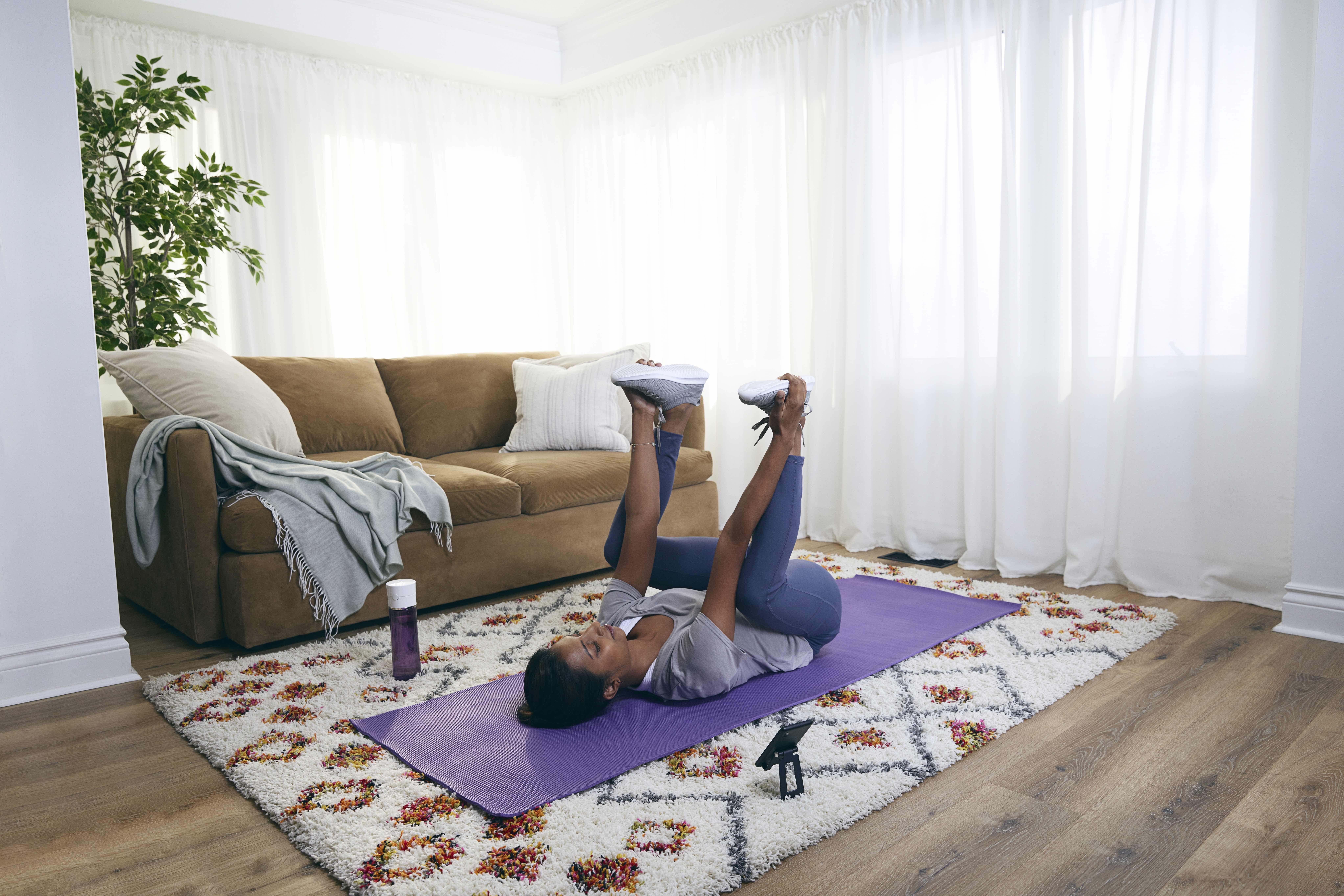 Woman lying on yoga mat gripping the bottoms of her feet