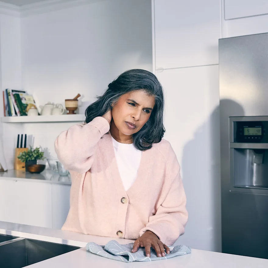 Woman-holding-her-neck-in-pain-at-her-kitchen
