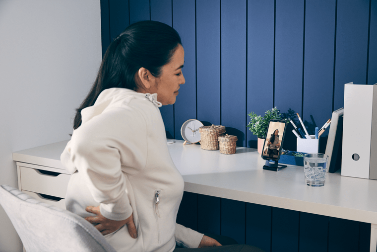 Person sitting at desk holding her back, back pain