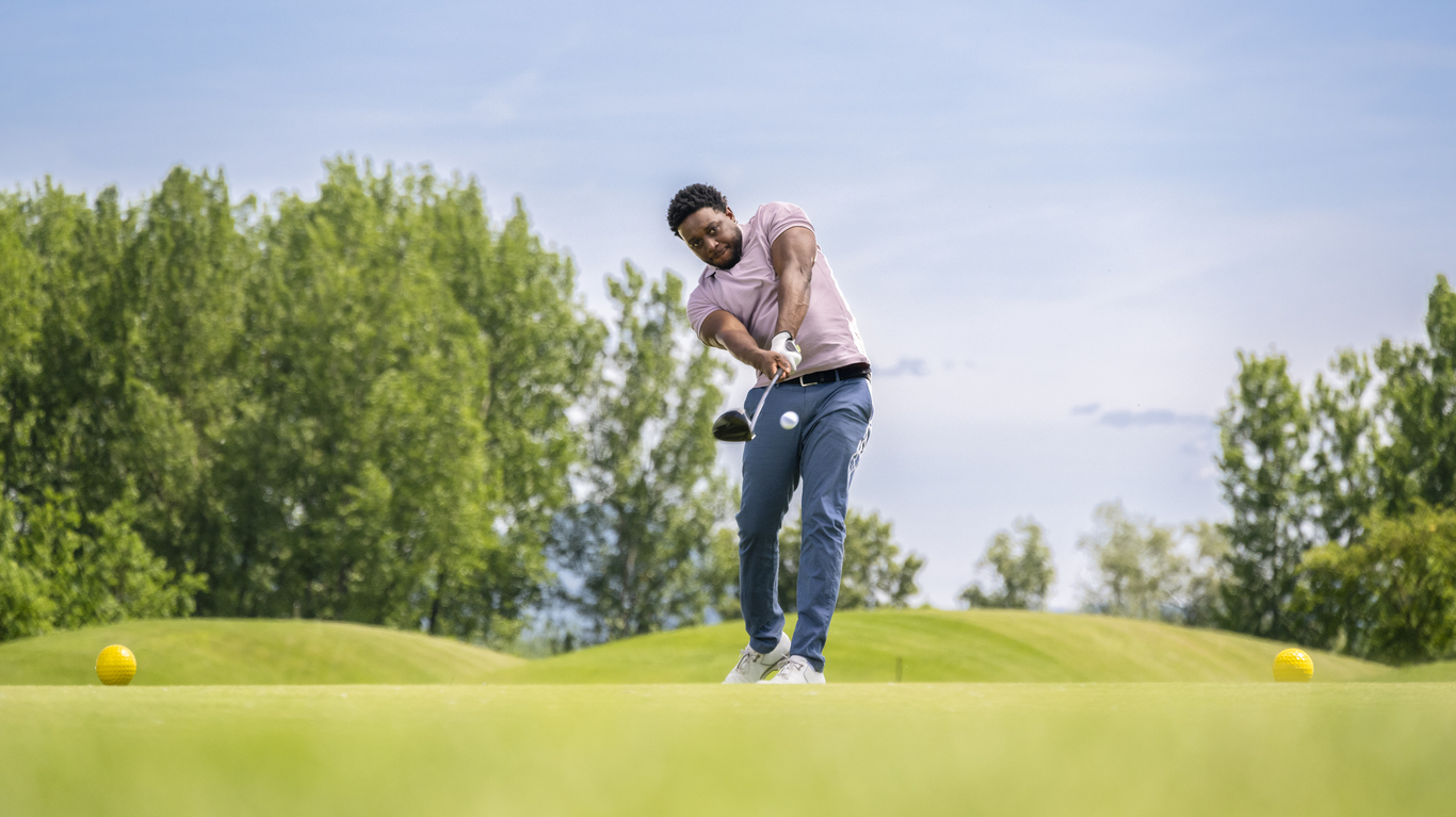 A golfer taking a swing on a sunny course, highlighting arm movement and form addressed in golfers elbow exercises