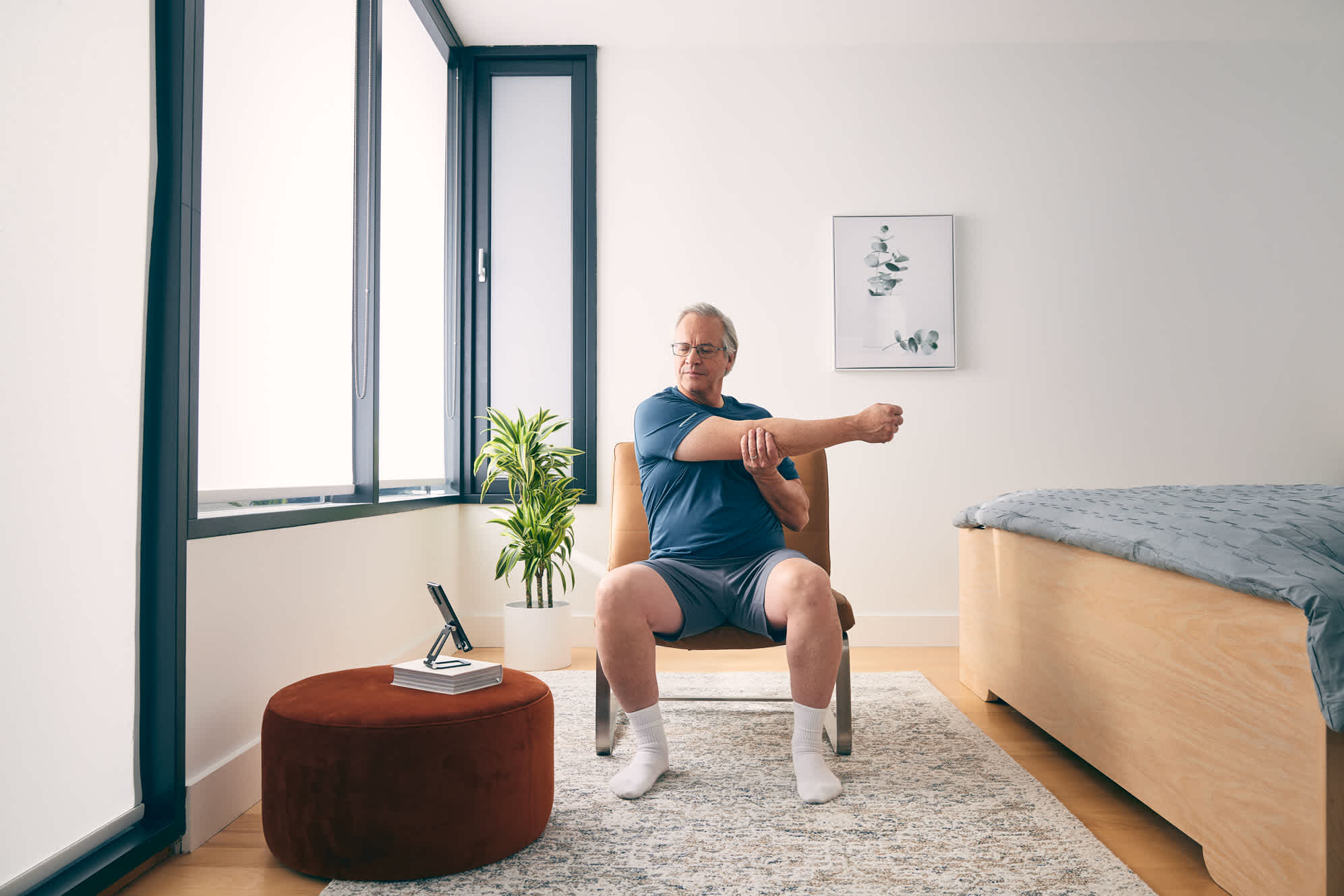 elderly-man-sitting-at-home-cross-stretching-arms