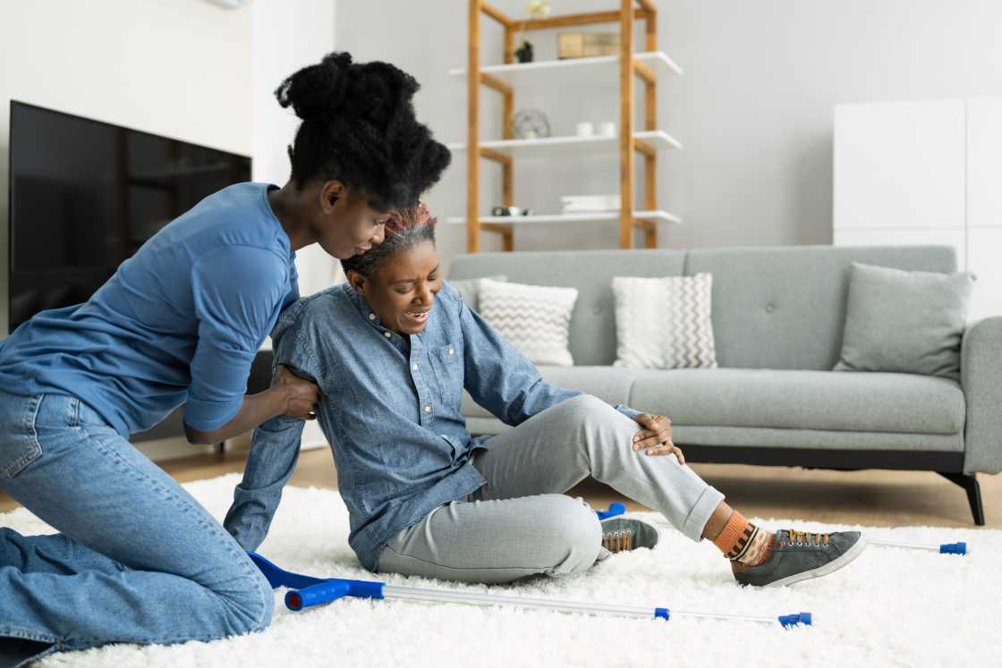 woman-helping-older-lady-get-up-from-sitting-on-the-floor-at-home