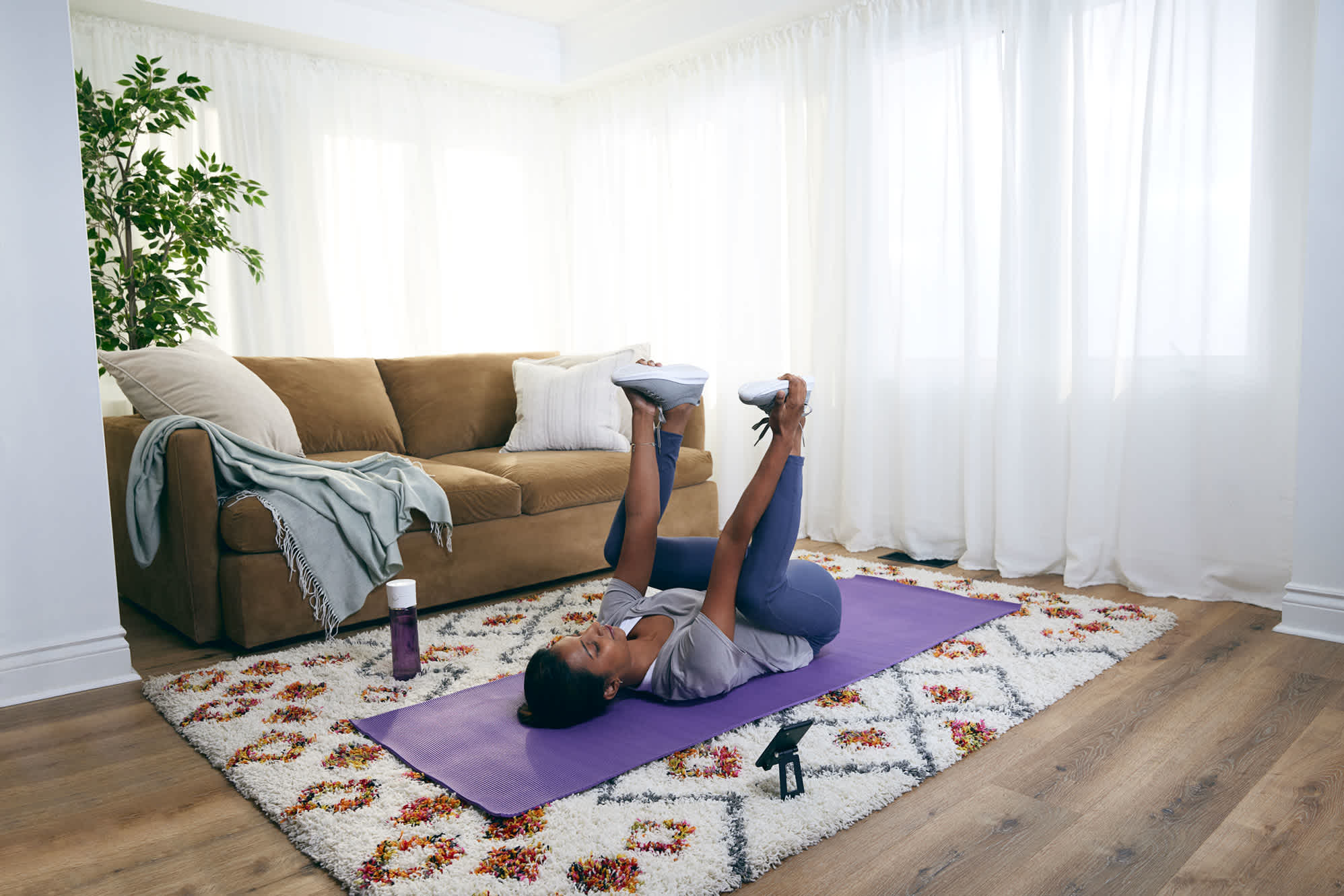 Woman-at-home-doing-happy-baby-stretch-on-yoga-mat