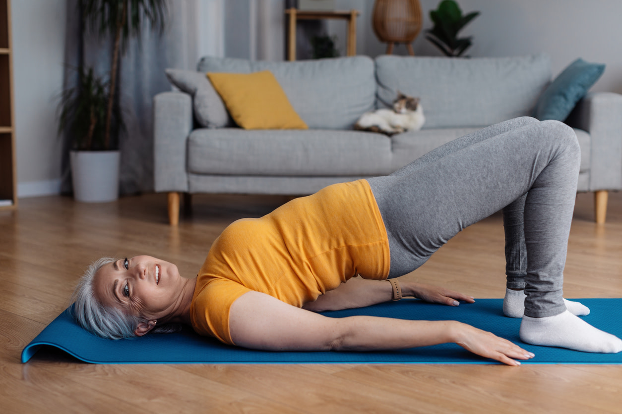 Elderly-woman-doing-glute-bridges-on-yoga-mat-at-home