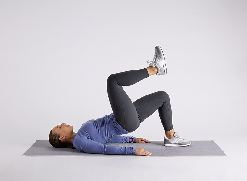 Person in blue long-sleeve top and black leggings performing physical therapy exercises