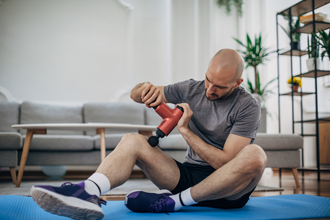 man using massage gun for knee pain