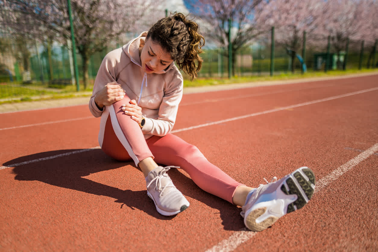 woman-sitting-in-pain-touching-her-knee-in-a-running-track
