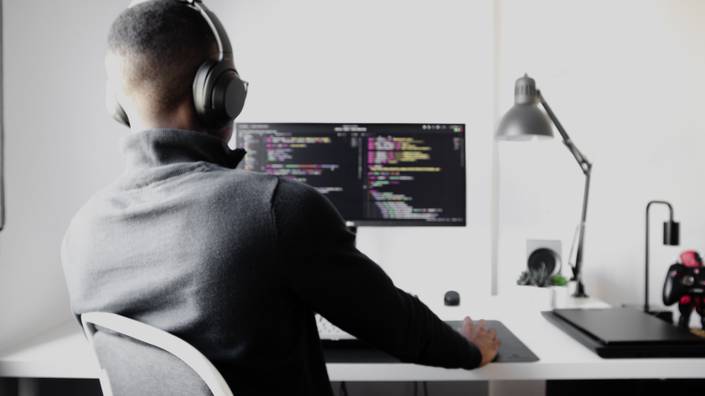 Dynamic configurations concept: Person with headphones coding on a computer at a desk