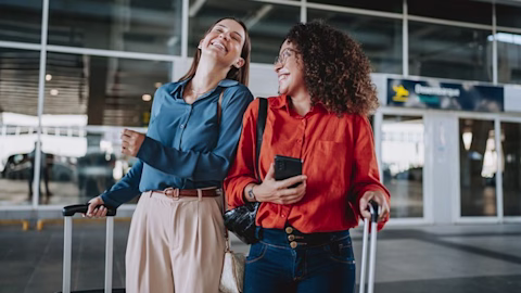 Two friends laughing as they leave an airport. Two friends laughing as they leave an airport.