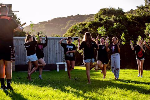 A group of teenage girls outside on the grass learning a First Nations traditional dance A group of teenage girls outside on the grass learning a First Nations traditional dance