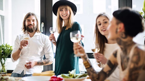 A group of friends at a table celebrating holding wine glasses A group of friends at a table celebrating holding wine glasses