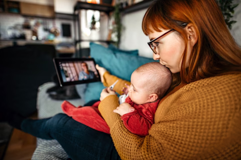 Mother holding a baby, consulting with doctor over a telehealth video call on digital tablet. Mother holding a baby, consulting with doctor over a telehealth video call on digital tablet.