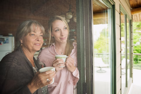 Woman and her mother looking out the window Woman and her mother looking out the window