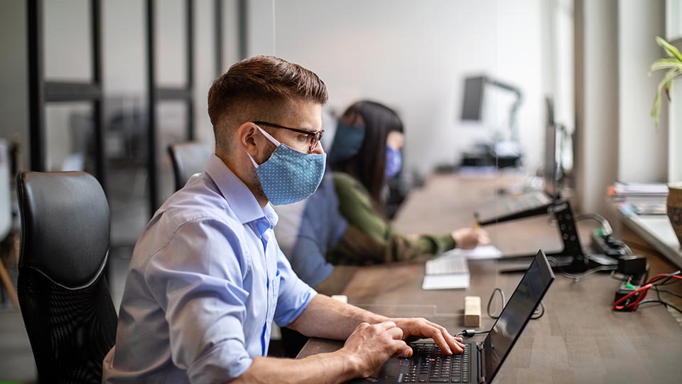 A masked contact tracer working away on his laptop