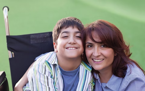 Boy in a wheelchair smiling with his mum Boy in a wheelchair smiling with his mum
