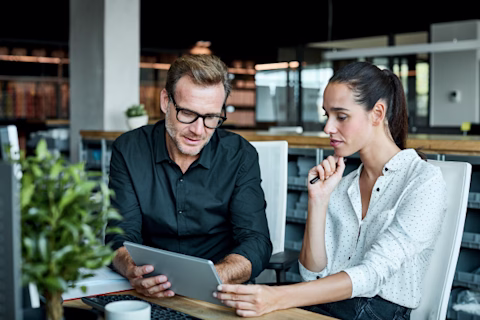 Two office workers using a digital tablet Two office workers using a digital tablet